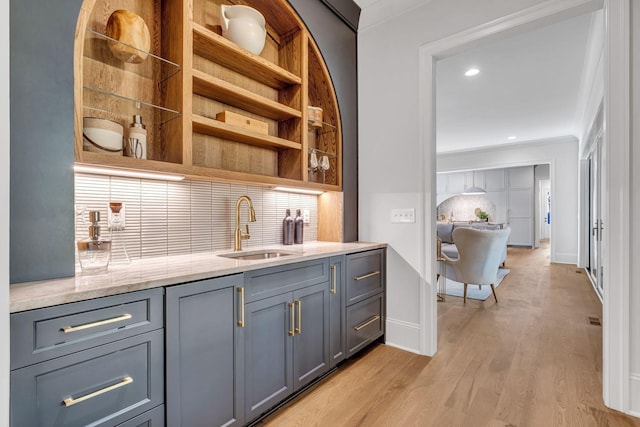 bar with light hardwood / wood-style floors, sink, gray cabinets, and ornamental molding