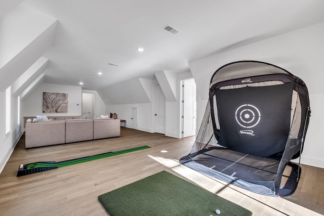 interior space featuring lofted ceiling, golf simulator, and hardwood / wood-style floors