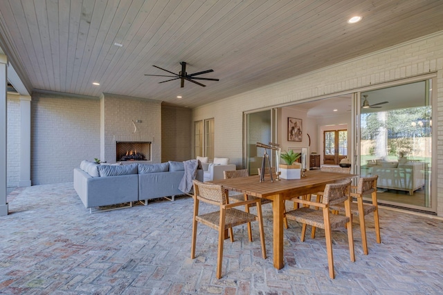 dining room featuring ceiling fan, wooden ceiling, brick wall, and an outdoor brick fireplace