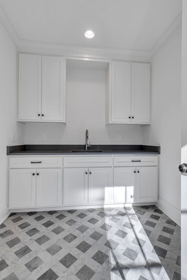 kitchen featuring sink, white cabinetry, and crown molding