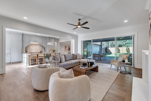 living room featuring ceiling fan, ornamental molding, and light hardwood / wood-style floors