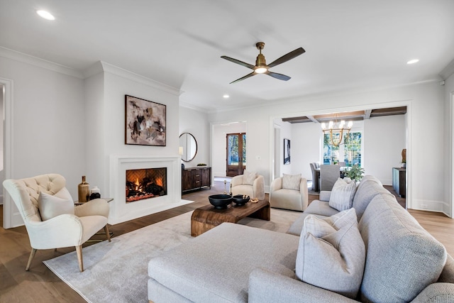 living room with ceiling fan with notable chandelier, ornamental molding, and light hardwood / wood-style floors