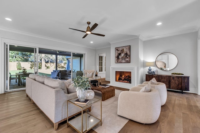 living room featuring ceiling fan, ornamental molding, and light hardwood / wood-style flooring