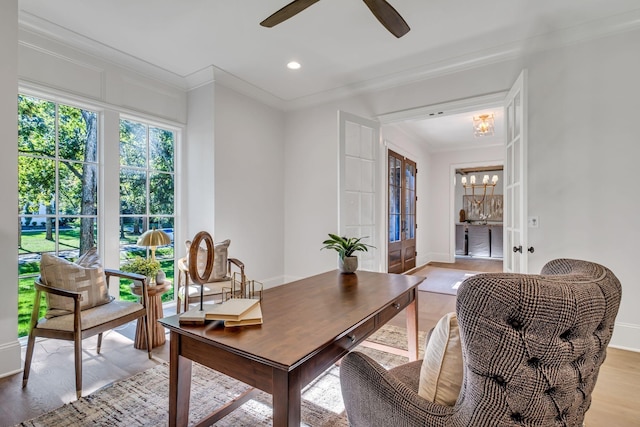 office space with light wood-type flooring, ornamental molding, ceiling fan with notable chandelier, and french doors