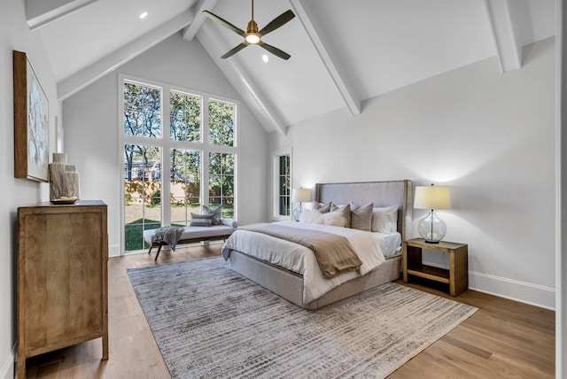 bedroom featuring ceiling fan, hardwood / wood-style floors, high vaulted ceiling, and beamed ceiling