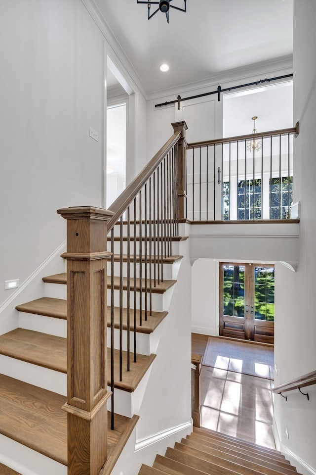 staircase with crown molding, french doors, and a notable chandelier