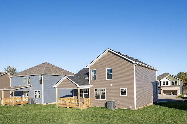 rear view of property featuring a deck, central air condition unit, and a lawn