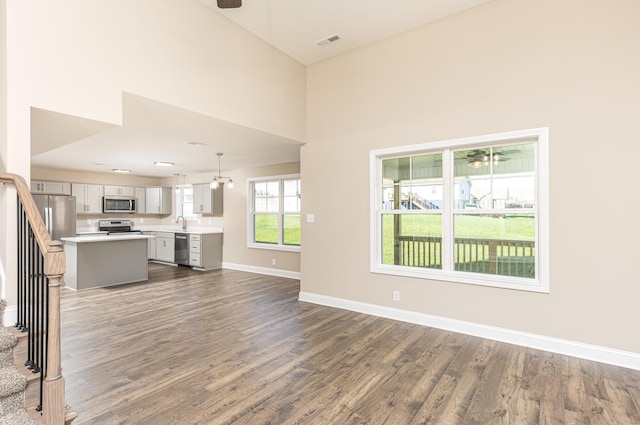 unfurnished living room with dark wood-type flooring, sink, and a high ceiling