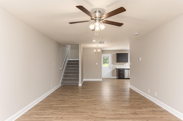 unfurnished living room featuring wood-type flooring and ceiling fan with notable chandelier