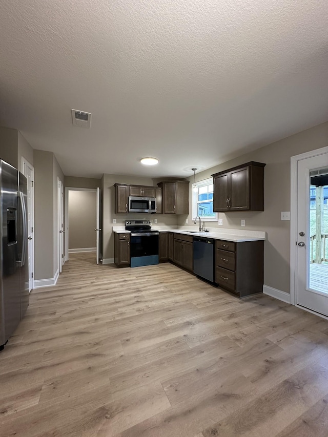 kitchen with sink, light hardwood / wood-style flooring, appliances with stainless steel finishes, dark brown cabinets, and a textured ceiling