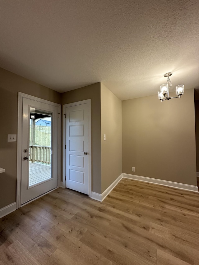 interior space with a textured ceiling, a notable chandelier, and light hardwood / wood-style floors