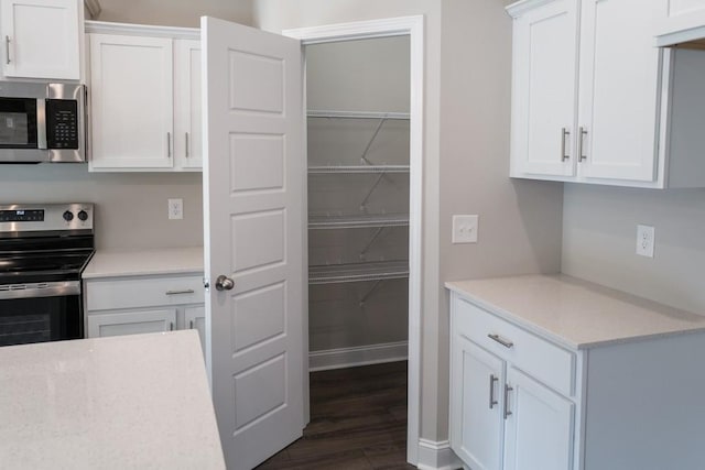 kitchen with dark wood-type flooring, stainless steel appliances, and white cabinetry