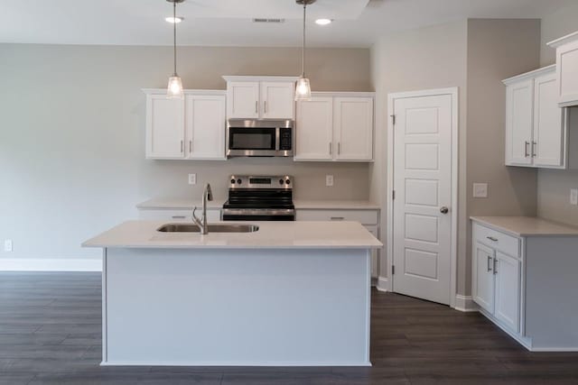 kitchen with appliances with stainless steel finishes, sink, white cabinets, and decorative light fixtures