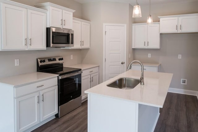 kitchen featuring decorative light fixtures, white cabinetry, stainless steel appliances, sink, and a center island with sink