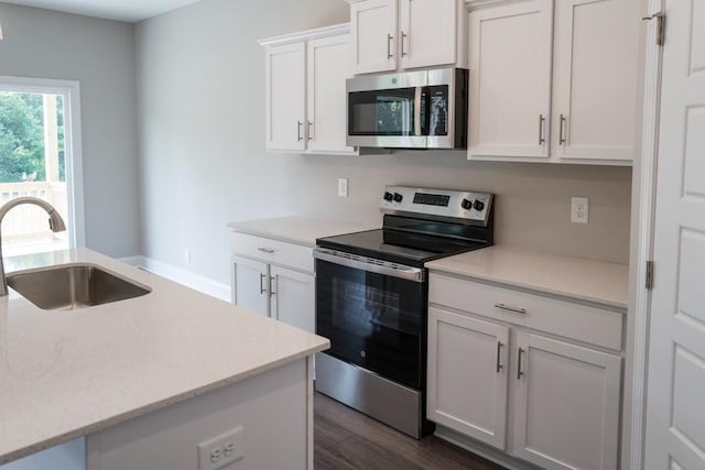 kitchen with dark hardwood / wood-style flooring, sink, stainless steel appliances, and white cabinetry