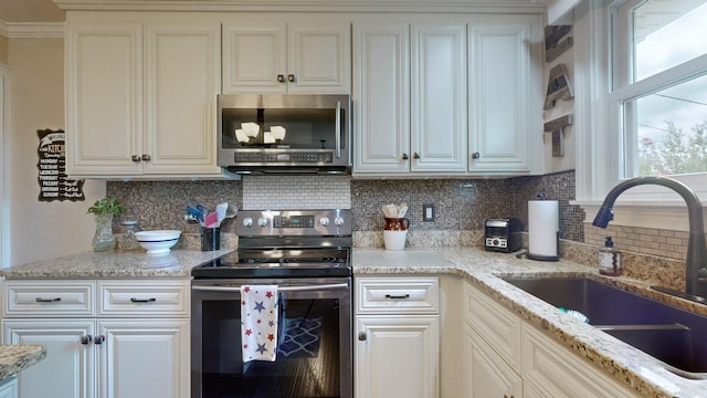 kitchen with light stone counters, sink, backsplash, and stainless steel appliances