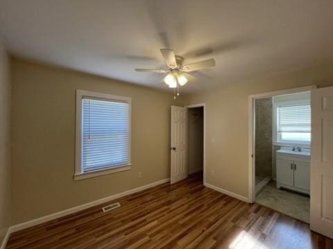 unfurnished bedroom with ceiling fan, ensuite bath, and hardwood / wood-style flooring