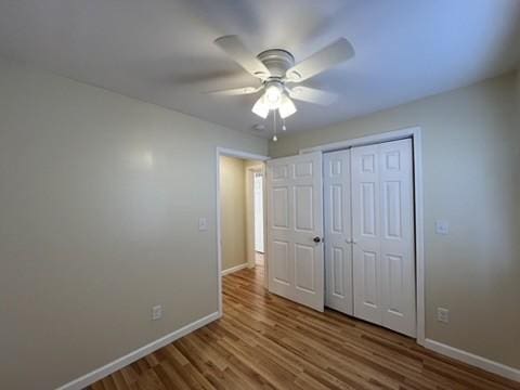 unfurnished bedroom with ceiling fan, a closet, and hardwood / wood-style flooring