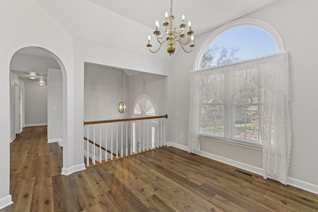 unfurnished dining area featuring high vaulted ceiling, dark wood-type flooring, and a chandelier