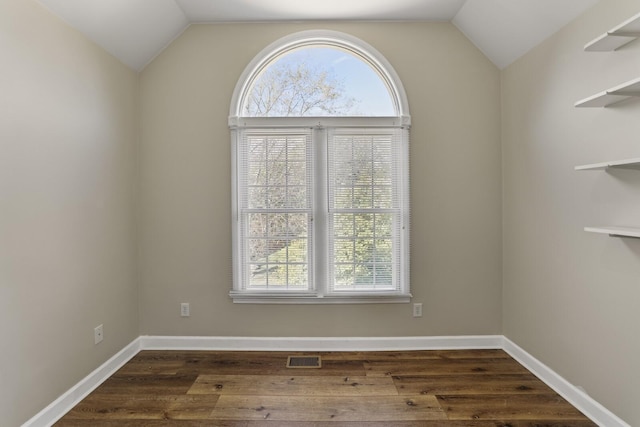 empty room with dark hardwood / wood-style flooring and vaulted ceiling