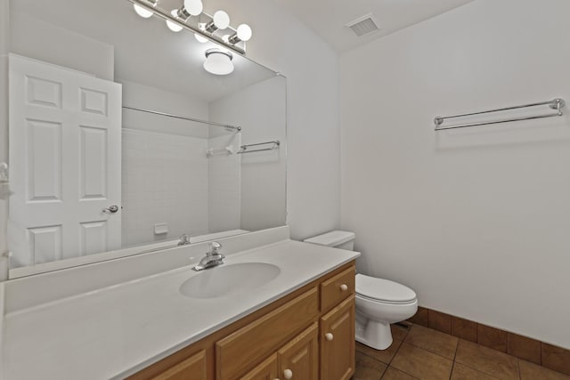 bathroom with toilet, vanity, tile patterned flooring, and walk in shower