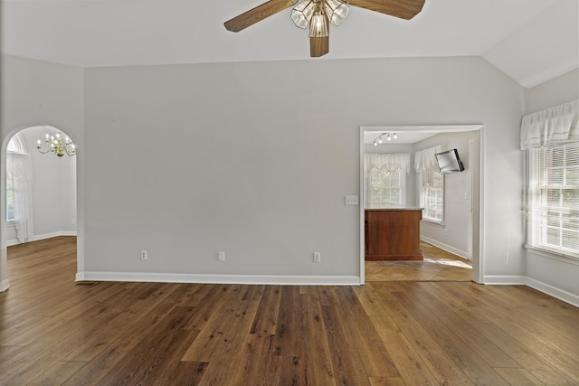 empty room featuring hardwood / wood-style flooring, lofted ceiling, and ceiling fan with notable chandelier