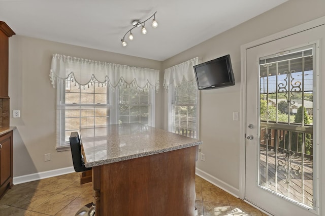 kitchen with light stone countertops, tile patterned flooring, and a healthy amount of sunlight