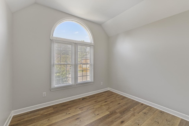 unfurnished room featuring lofted ceiling and wood-type flooring