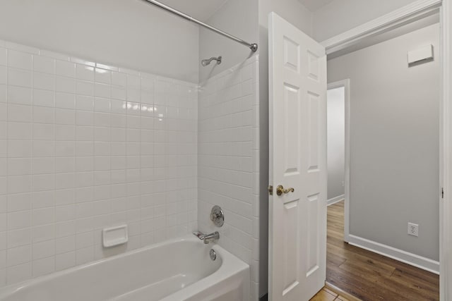 bathroom featuring hardwood / wood-style flooring and washtub / shower combination