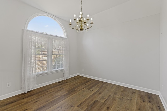 spare room with a wealth of natural light, dark hardwood / wood-style floors, and a notable chandelier