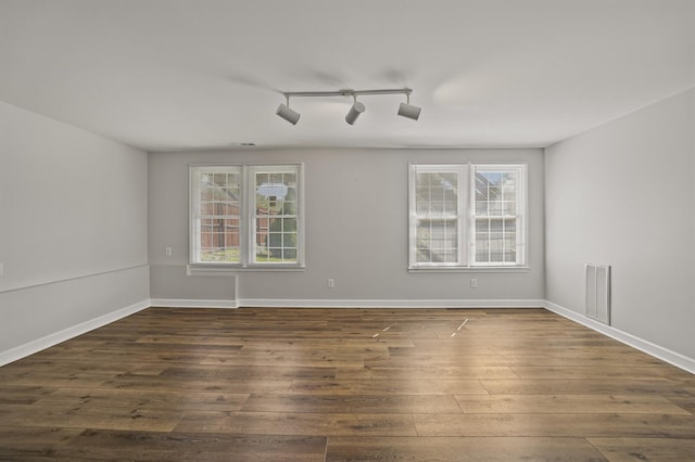 empty room featuring dark hardwood / wood-style flooring and track lighting