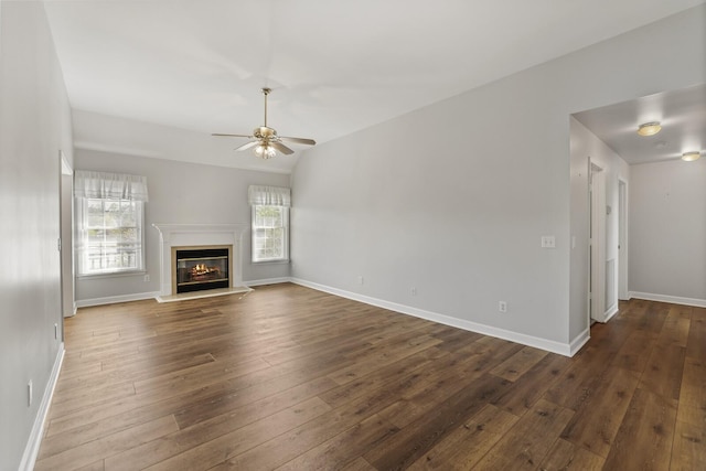 unfurnished living room featuring vaulted ceiling, dark wood-type flooring, a healthy amount of sunlight, and ceiling fan