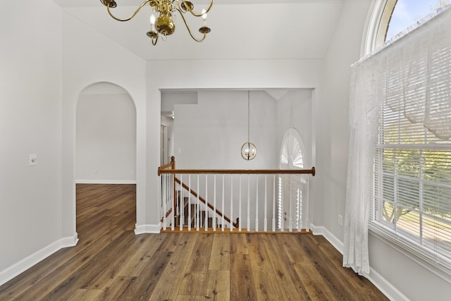 hallway featuring lofted ceiling, dark hardwood / wood-style floors, and a notable chandelier