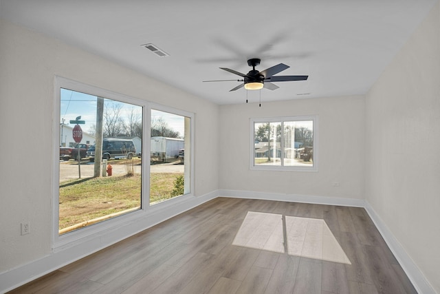 spare room with ceiling fan, a healthy amount of sunlight, and wood-type flooring