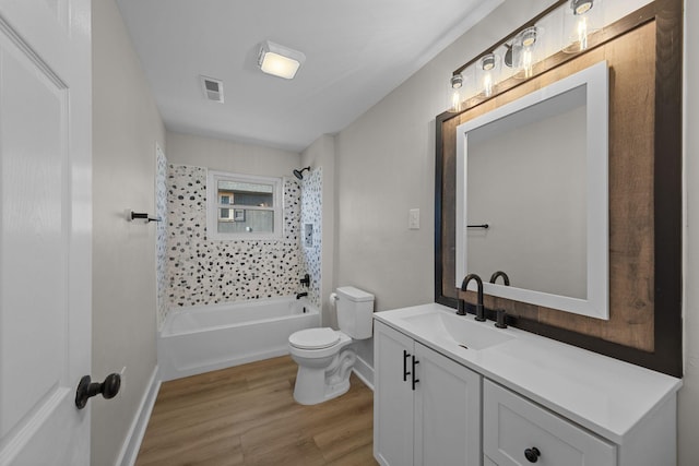 full bathroom with wood-type flooring, tiled shower / bath combo, vanity, and toilet