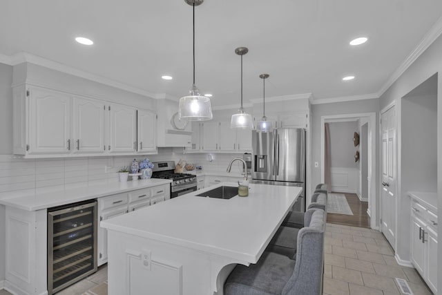 kitchen with sink, appliances with stainless steel finishes, an island with sink, white cabinets, and beverage cooler