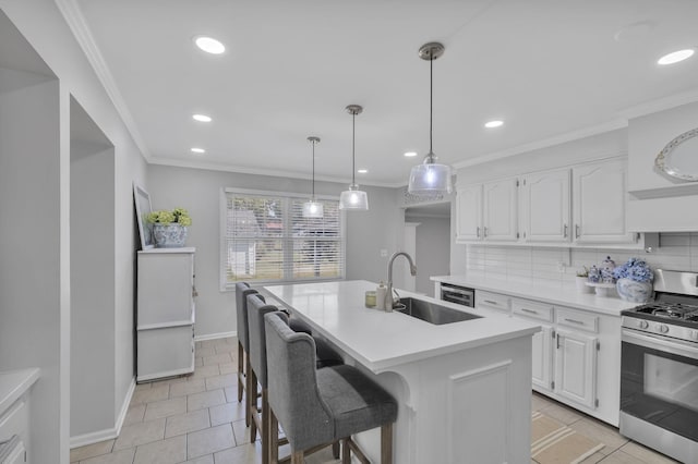 kitchen featuring tasteful backsplash, a center island with sink, sink, stainless steel range with gas cooktop, and white cabinets