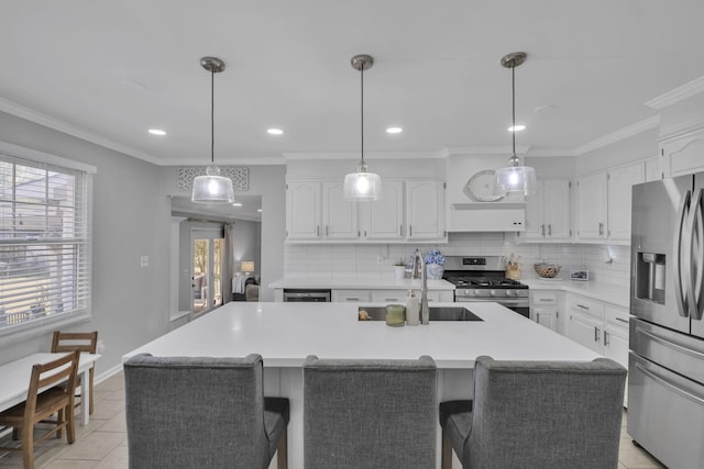 kitchen featuring white cabinetry, stainless steel appliances, and a center island with sink