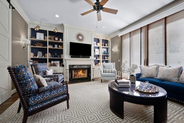 living room featuring hardwood / wood-style floors, a high end fireplace, built in features, ornamental molding, and ceiling fan