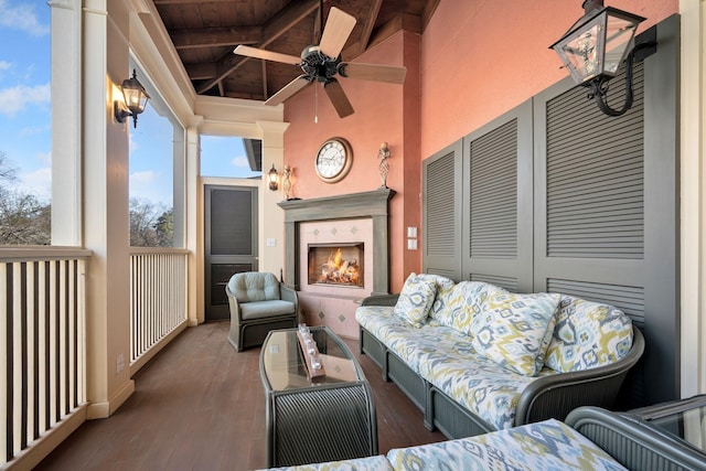 sunroom featuring ceiling fan, vaulted ceiling with beams, an outdoor fireplace, and wood ceiling