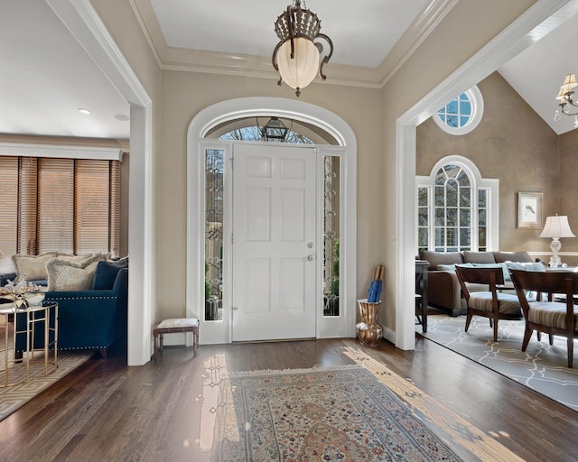 foyer featuring high vaulted ceiling, dark wood-type flooring, crown molding, and a chandelier