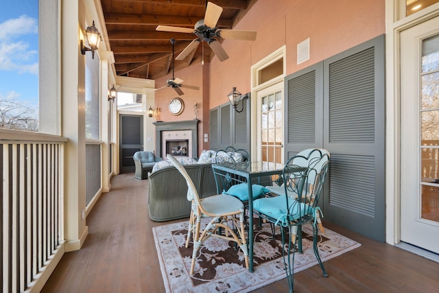 sunroom with ceiling fan, vaulted ceiling with beams, exterior fireplace, and wooden ceiling