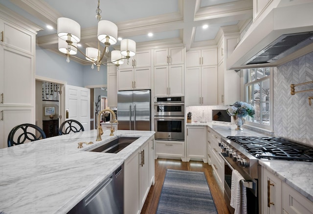 kitchen with premium range hood, hanging light fixtures, high end appliances, light stone counters, and sink