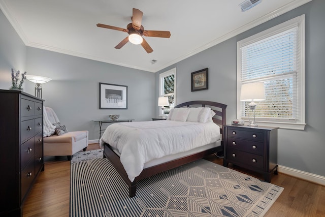 bedroom with ceiling fan, dark wood-type flooring, multiple windows, and crown molding