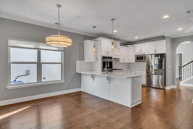 kitchen featuring kitchen peninsula, appliances with stainless steel finishes, pendant lighting, and white cabinets