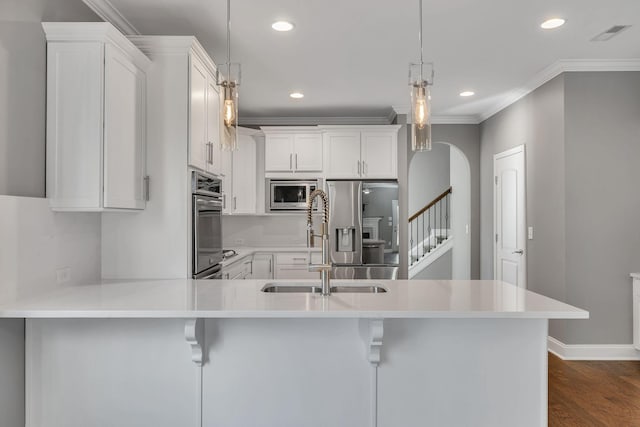 kitchen featuring decorative light fixtures, a kitchen bar, stainless steel appliances, white cabinets, and dark hardwood / wood-style flooring