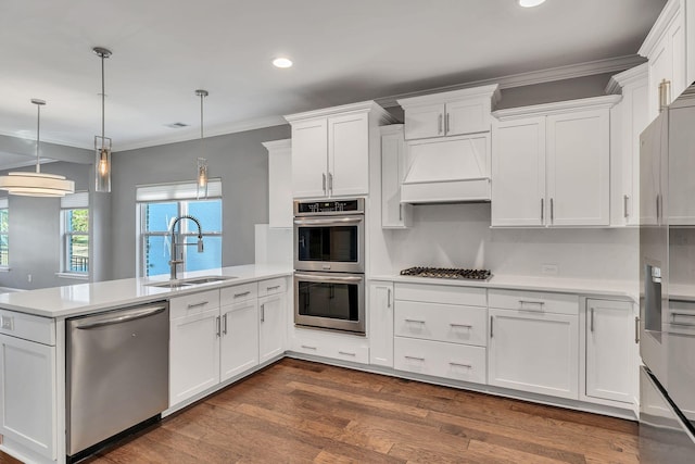 kitchen with white cabinetry, custom exhaust hood, stainless steel appliances, decorative light fixtures, and sink