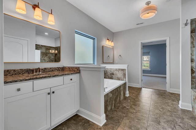 bathroom featuring tiled tub and vanity