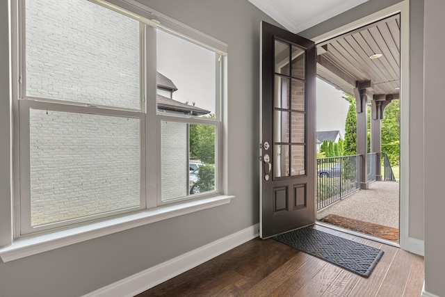 entrance foyer with ornamental molding and dark hardwood / wood-style floors