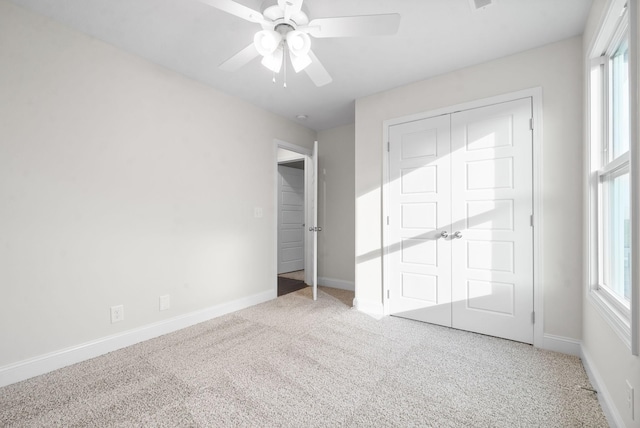 unfurnished bedroom with light carpet, ceiling fan, a closet, and multiple windows